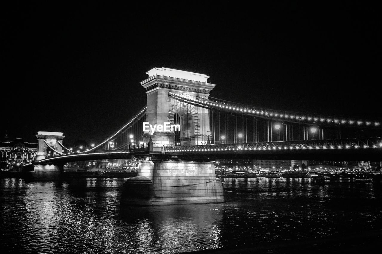 Illuminated bridge over river at night