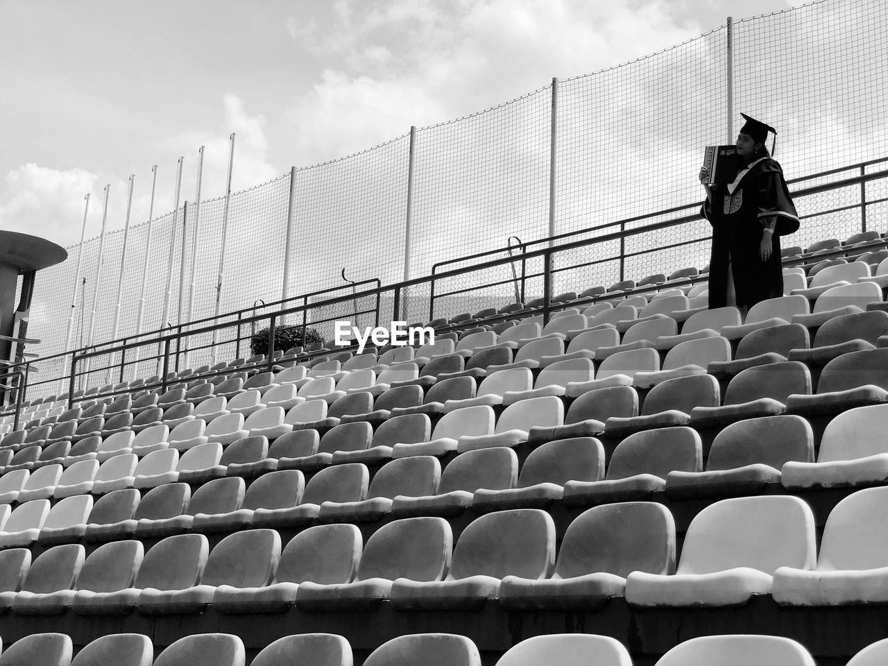 Woman wearing graduation gown while standing at stadium