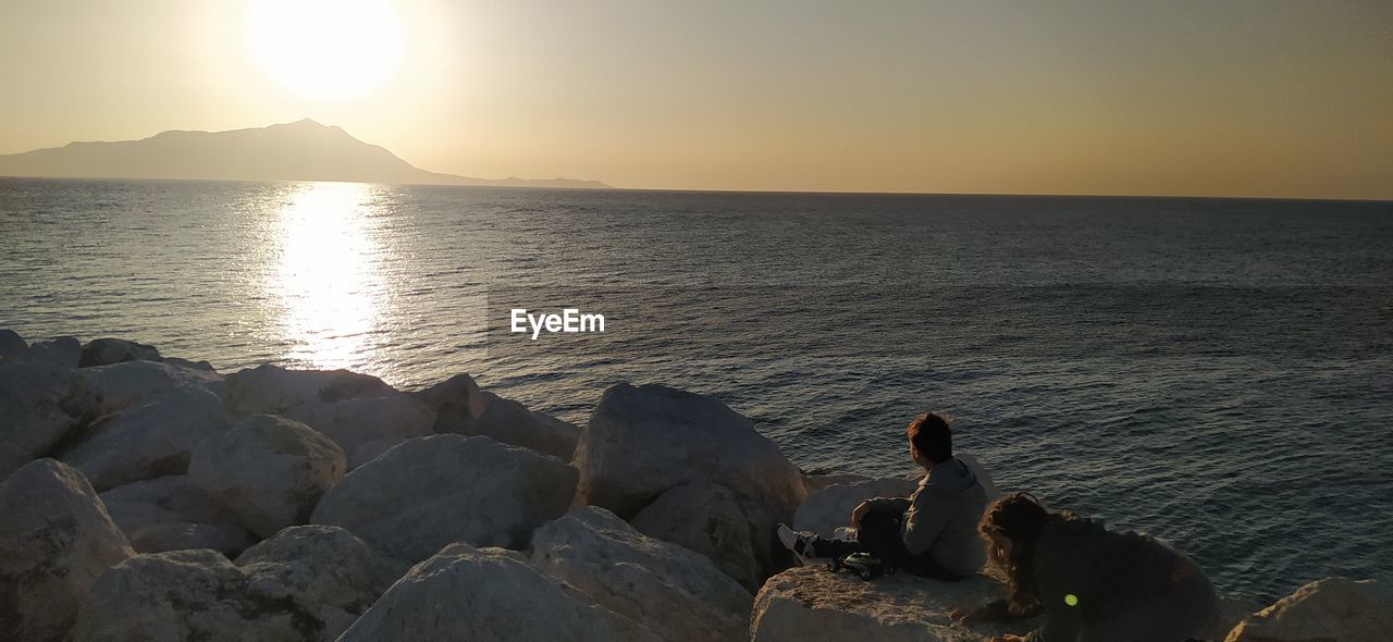 SCENIC VIEW OF ROCKS AT SEA AGAINST SKY DURING SUNSET