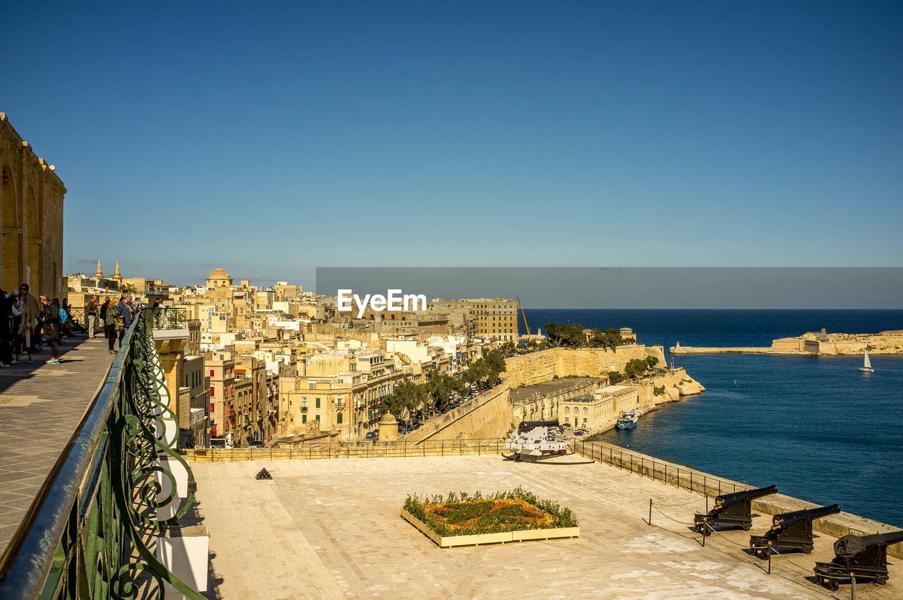 architecture, sky, water, built structure, vacation, sea, building exterior, nature, travel destinations, city, clear sky, coast, travel, cityscape, blue, building, history, landmark, the past, beach, tourism, horizon, sunny, sunlight, day, outdoors, high angle view, ancient history, horizon over water, land, ocean, no people, copy space, town