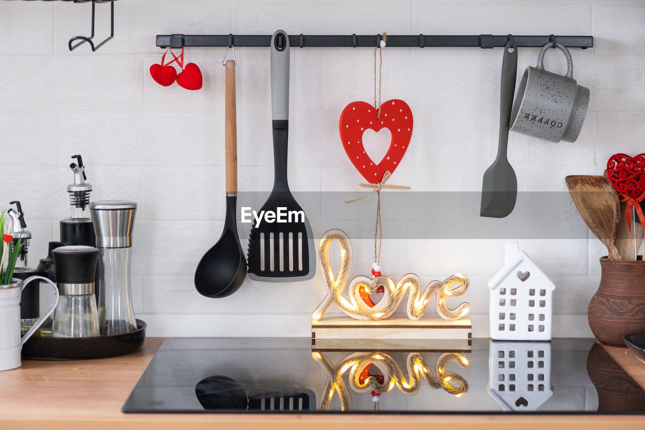 kitchen utensil, indoors, household equipment, no people, domestic room, kitchen, wood, heart shape, home, domestic kitchen, hanging, still life, lifestyles, domestic life, wooden spoon, room, red, variation, food and drink, spoon, arrangement, furniture, home interior, table, eating utensil, shelf, large group of objects