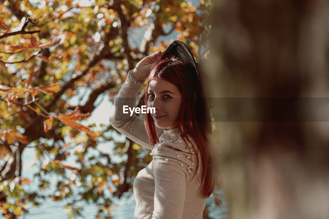 Portrait of smiling woman standing against tree