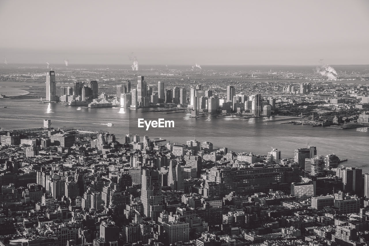 Aerial view of cityscape by river against sky