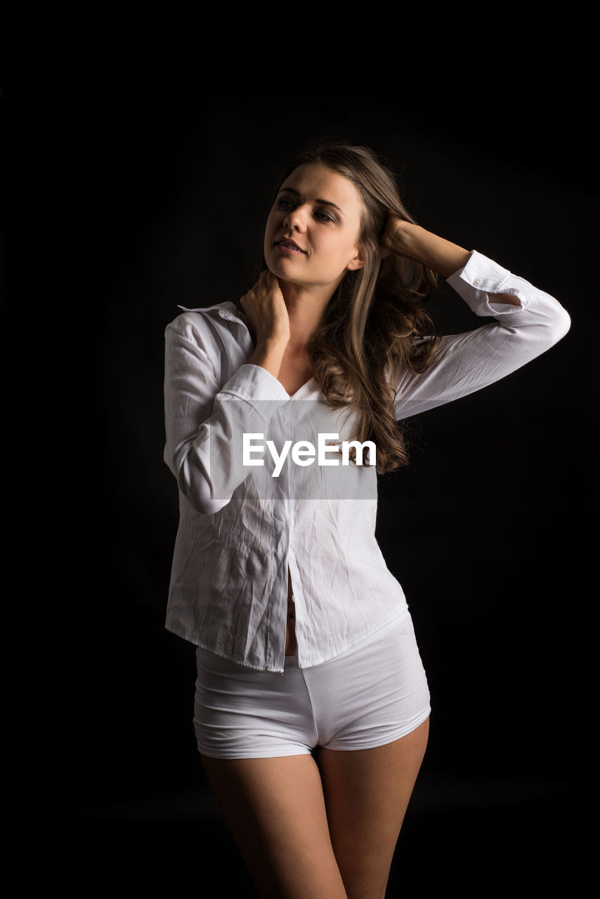 YOUNG WOMAN STANDING AGAINST WHITE BACKGROUND