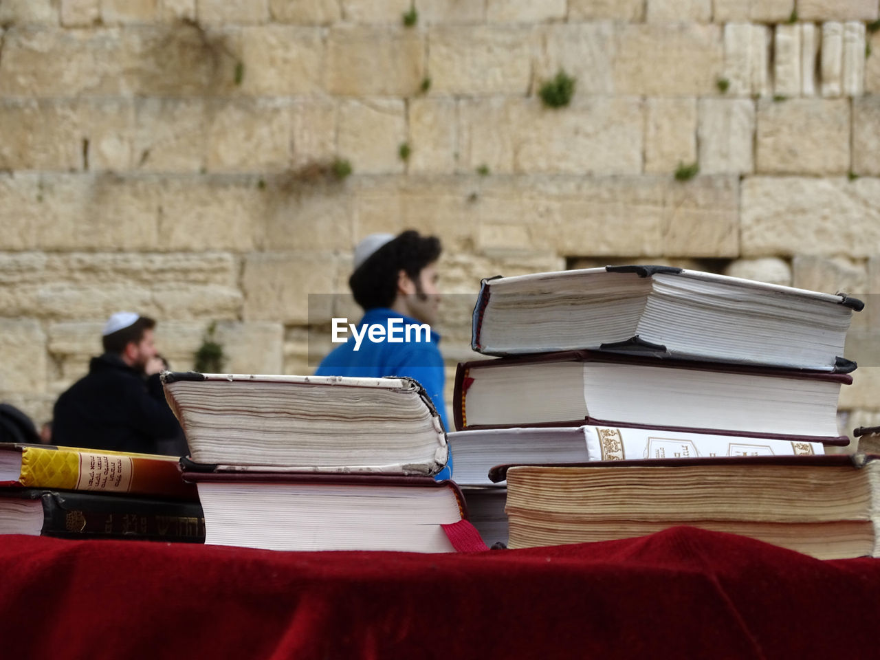 REAR VIEW OF MAN READING BOOK ON STACK