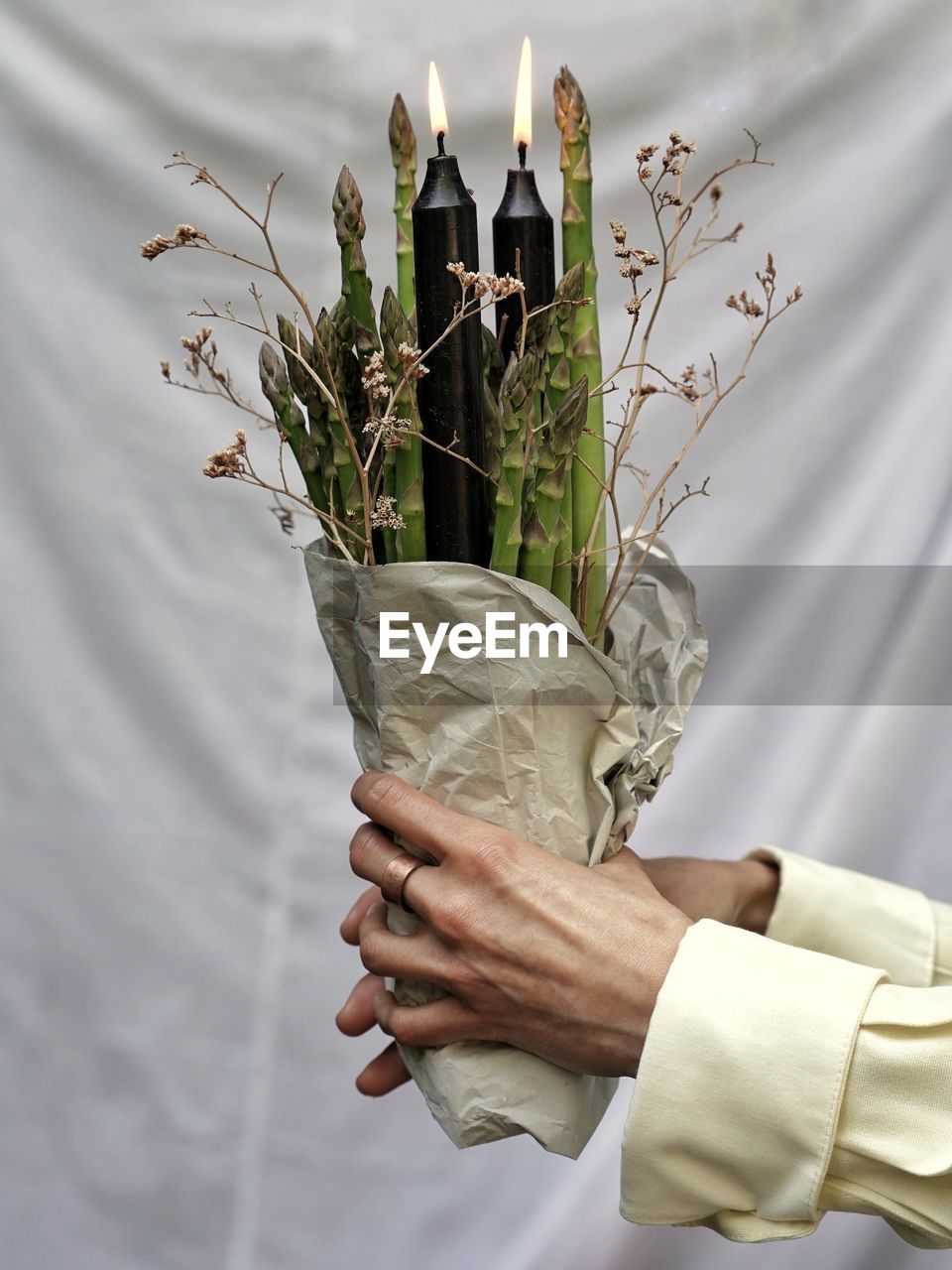 Cropped hand of woman holding plant with candle