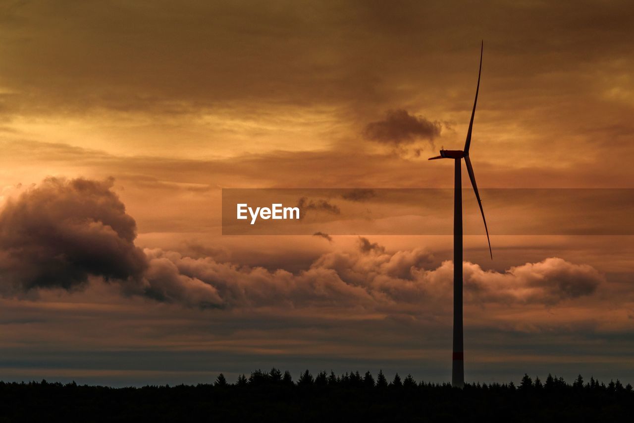 Silhouette wind turbines on landscape against sky during sunset