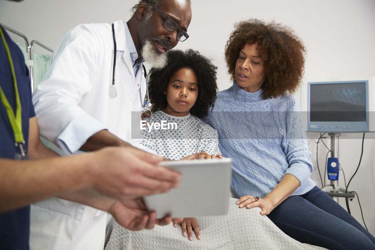 Doctor discussing treatment over tablet pc with patient and mother at hospital