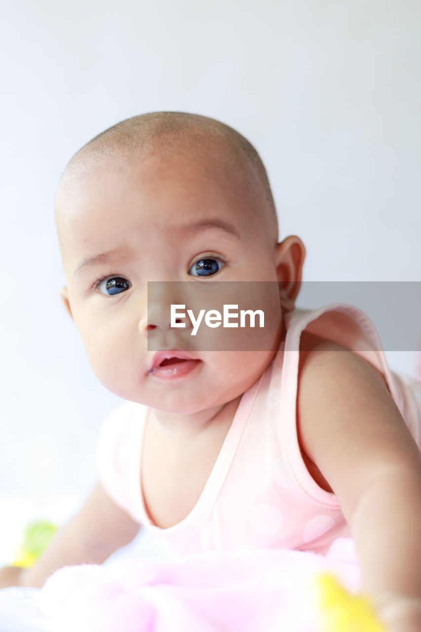 Close-up portrait of cute baby girl lying on bed at home