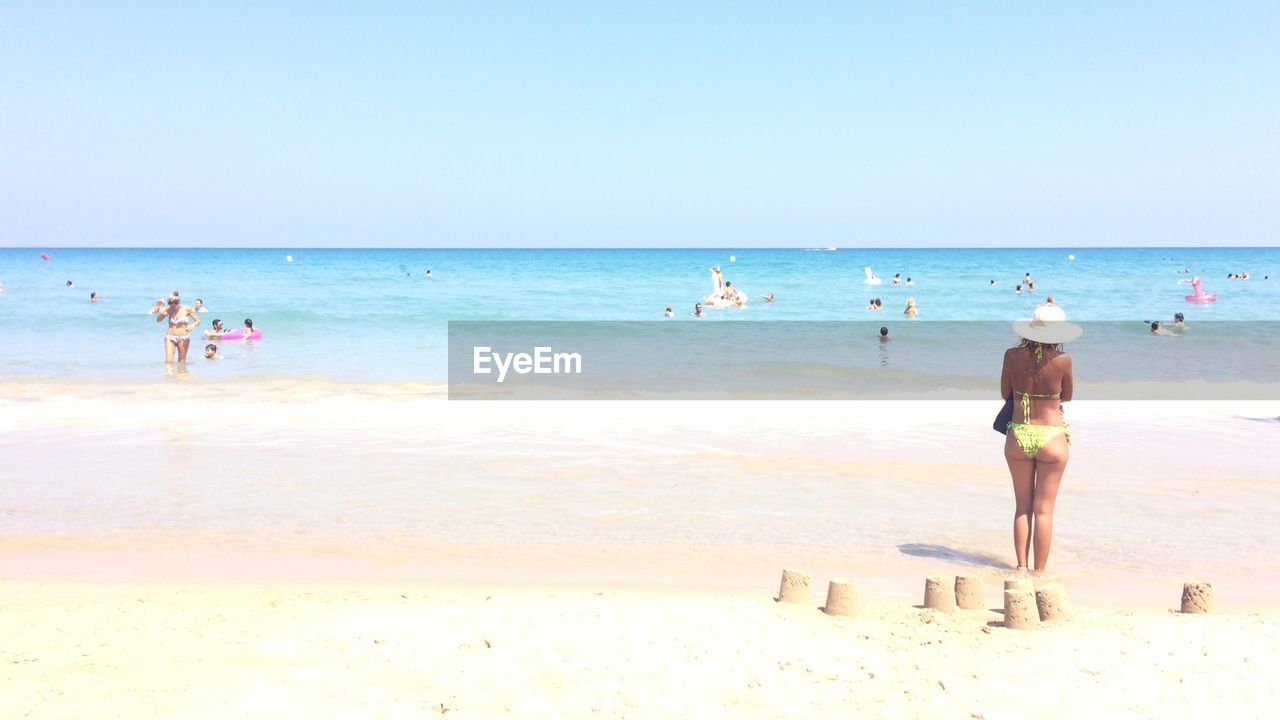 Rear view of people on beach against sky