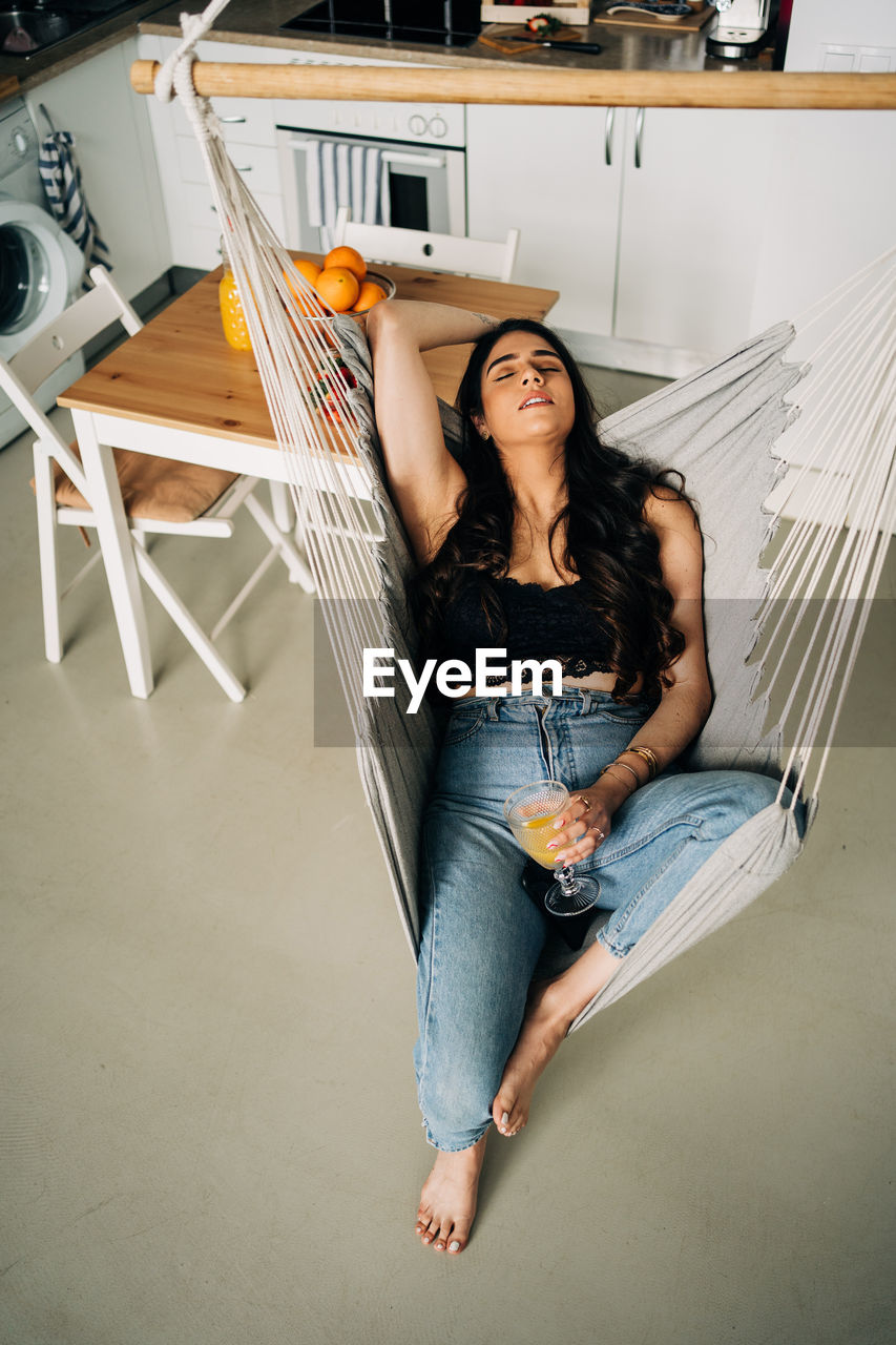 Young woman relaxing on hammock at home