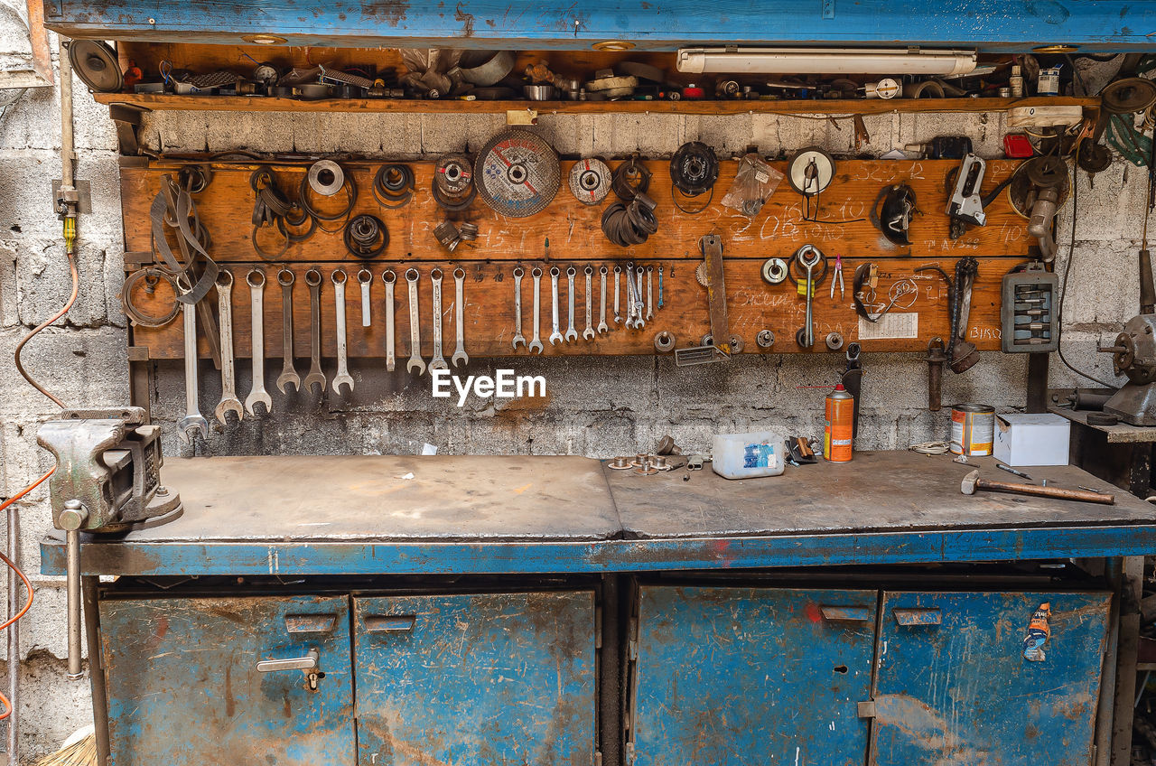 Old collection of various repair tools hangs on wall above table. workshop with tools.