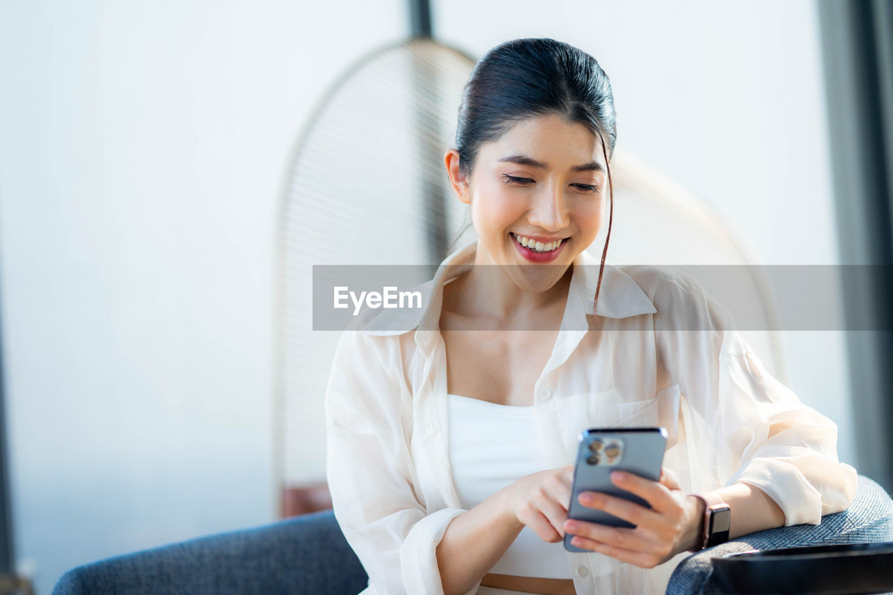 young woman using mobile phone while sitting at home