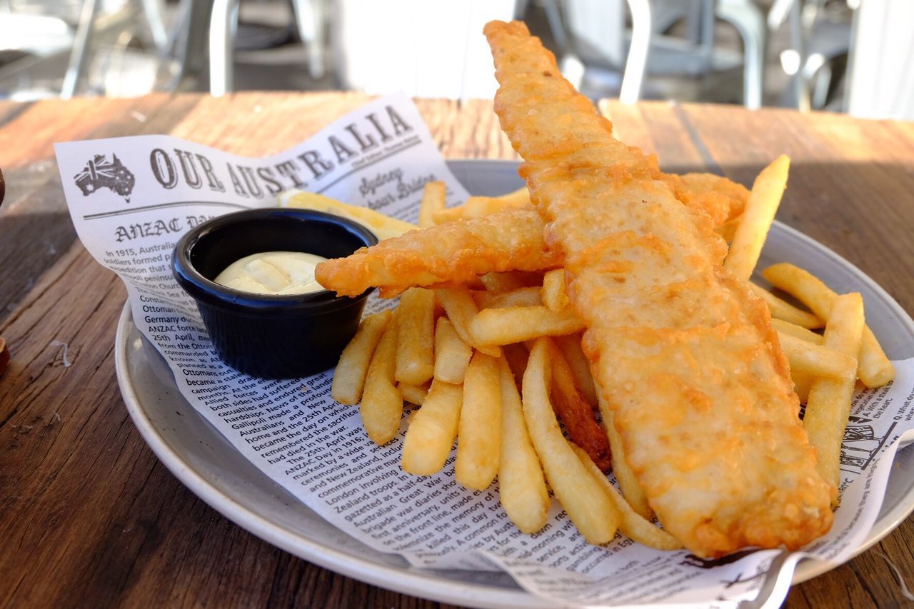 Close-up of fresh fish and chips served on table at sidewalk cafe