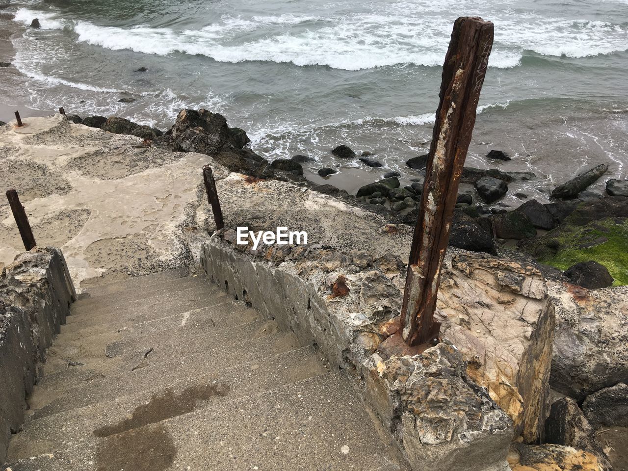 HIGH ANGLE VIEW OF WOODEN POST ON BEACH