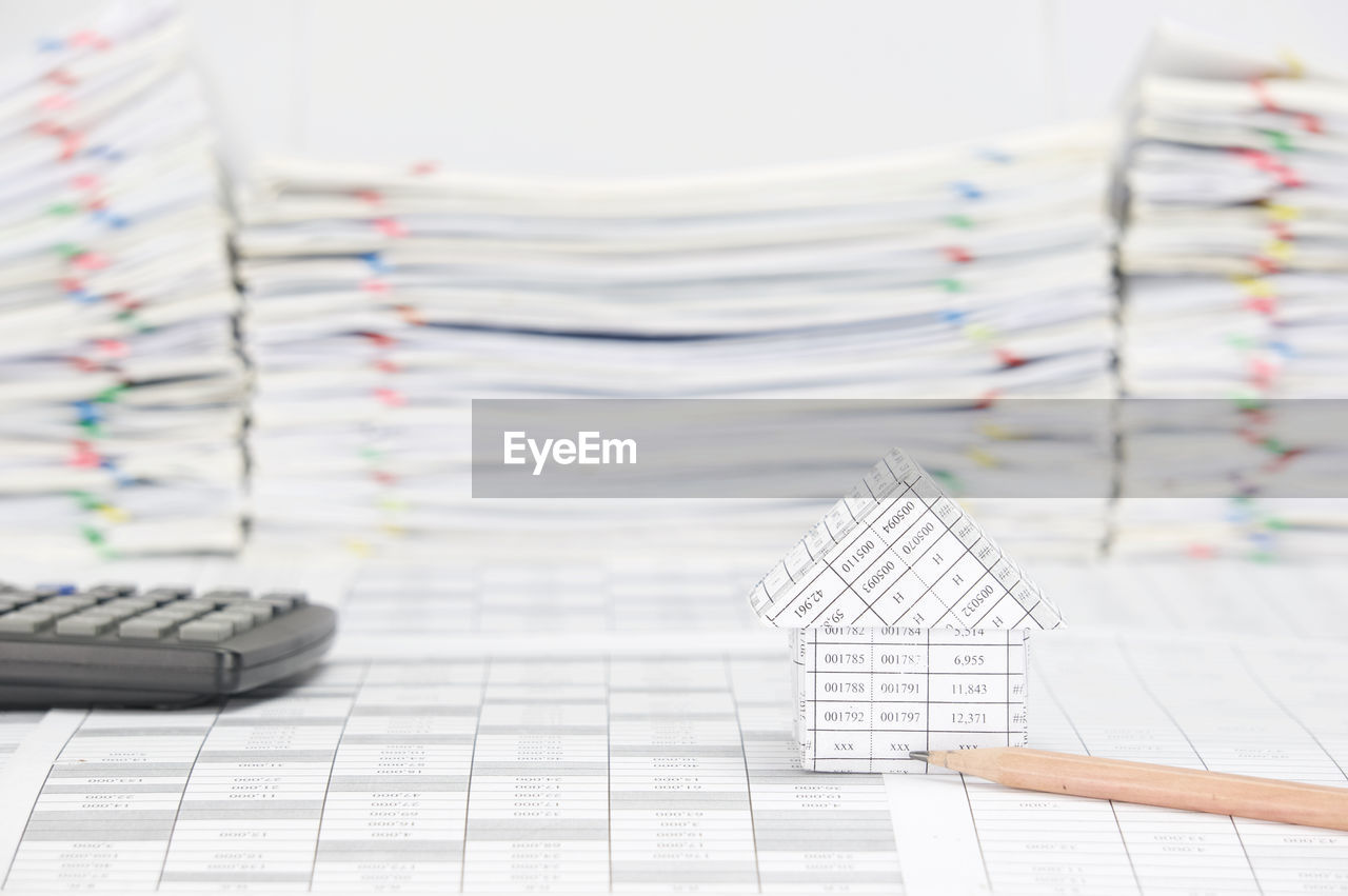 Close-up of model house with pencil and calculator on financial documents