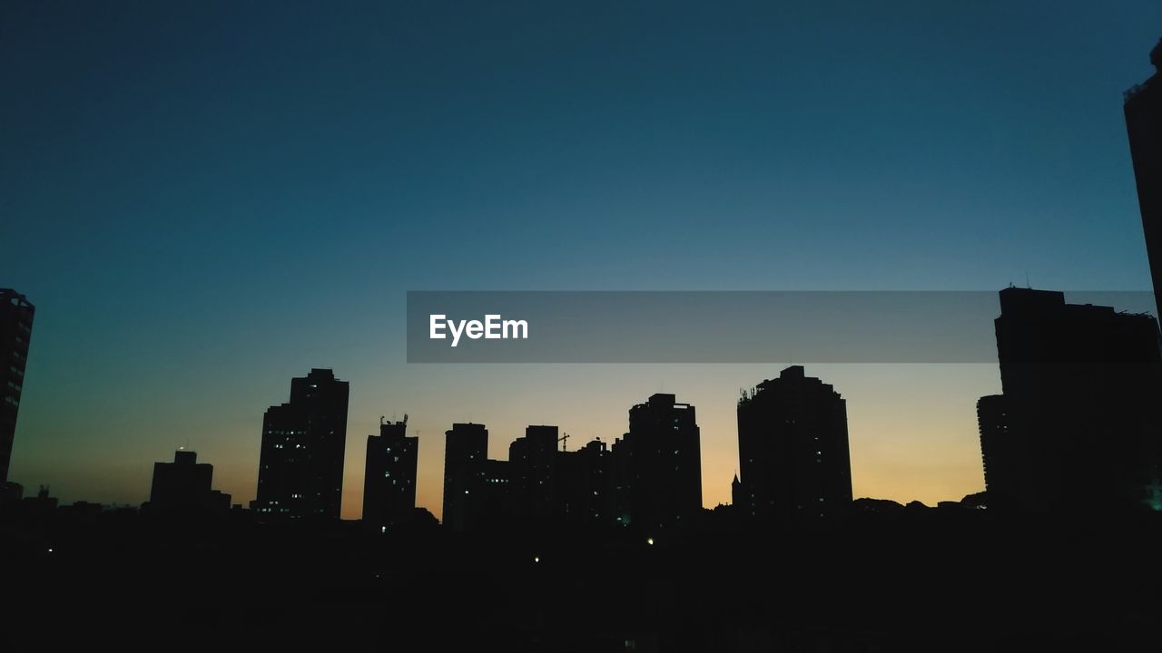 Silhouette buildings against sky at dusk