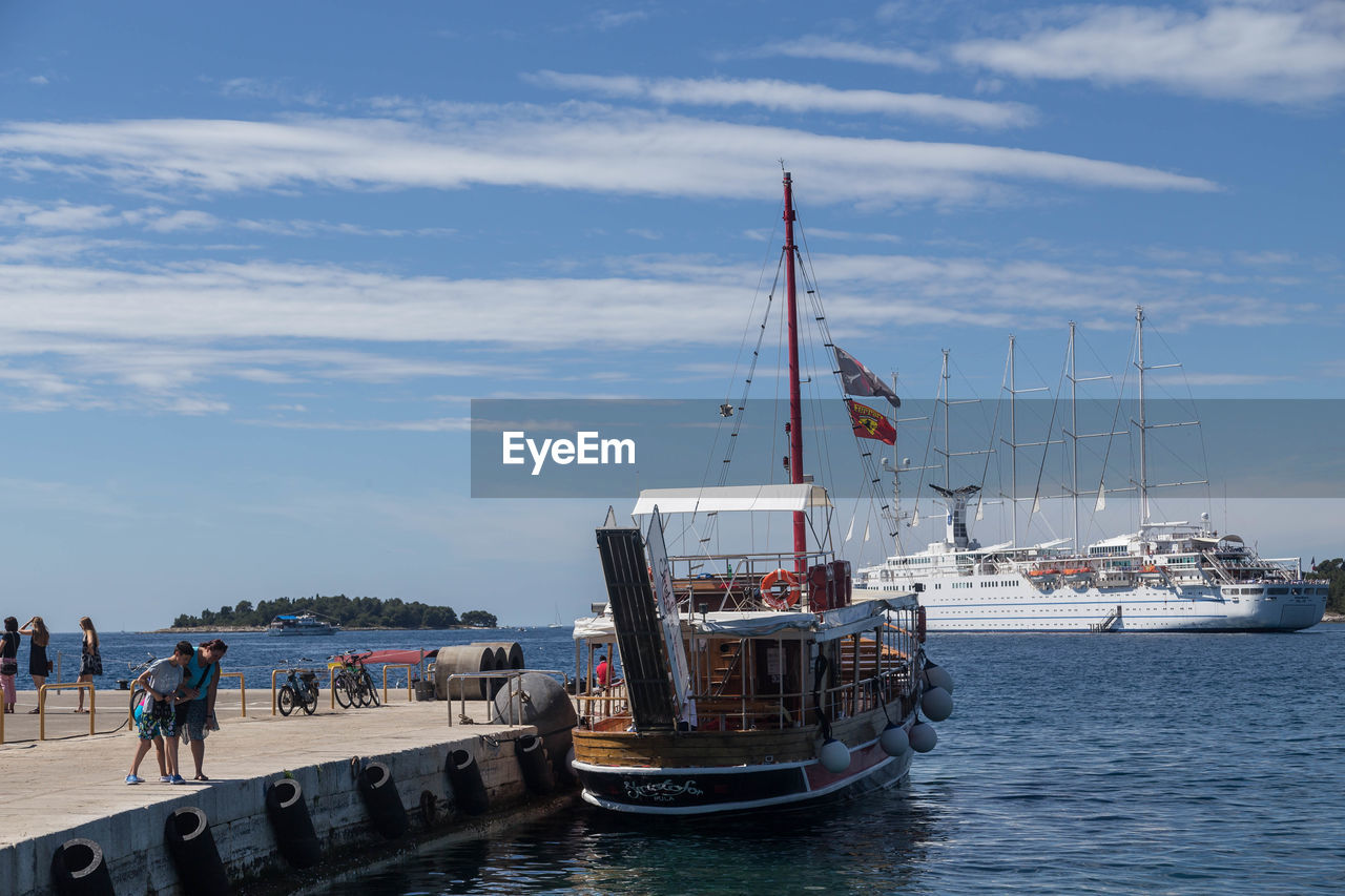 Sailboats on pier by sea against sky