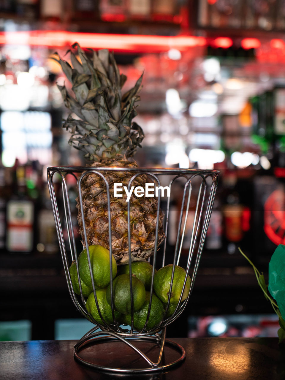 Close-up of pineapple and oranges in basket on table