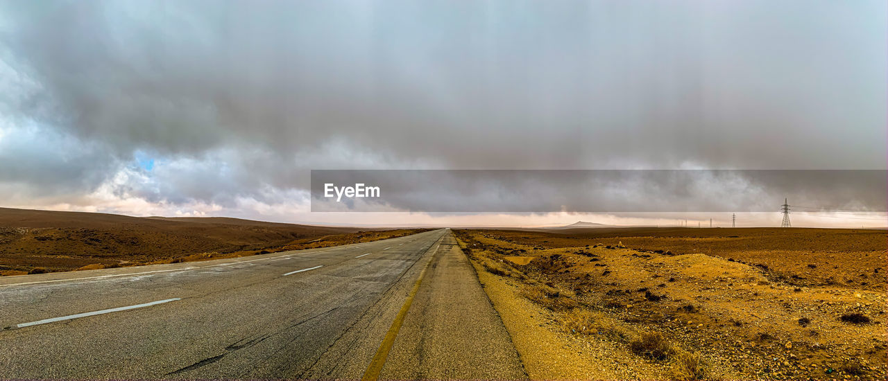 Road passing through desert against sky