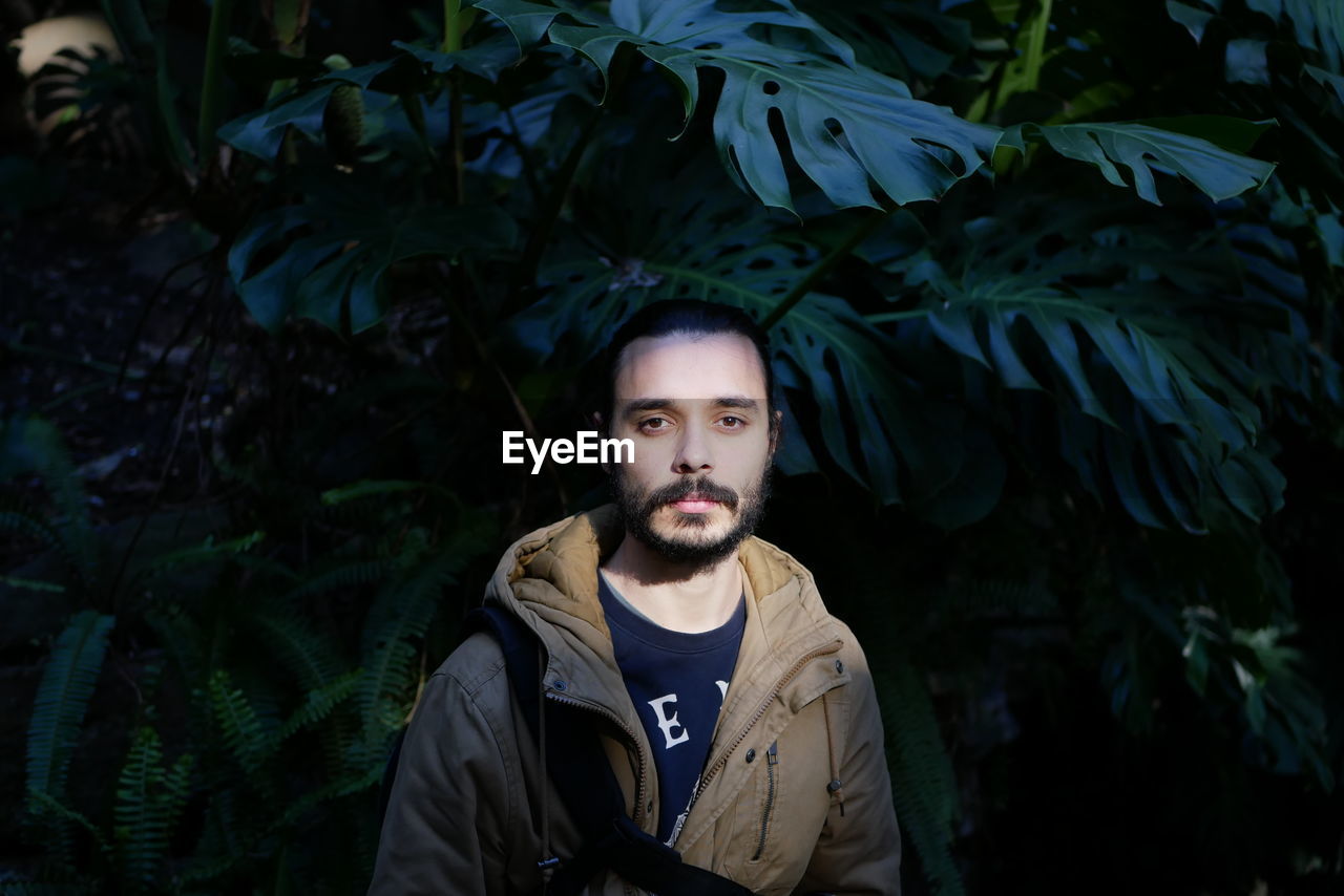 Portrait of man standing against tree