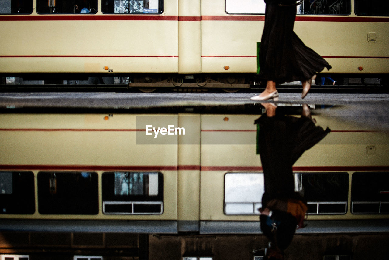 Low section of woman walking by tram in city