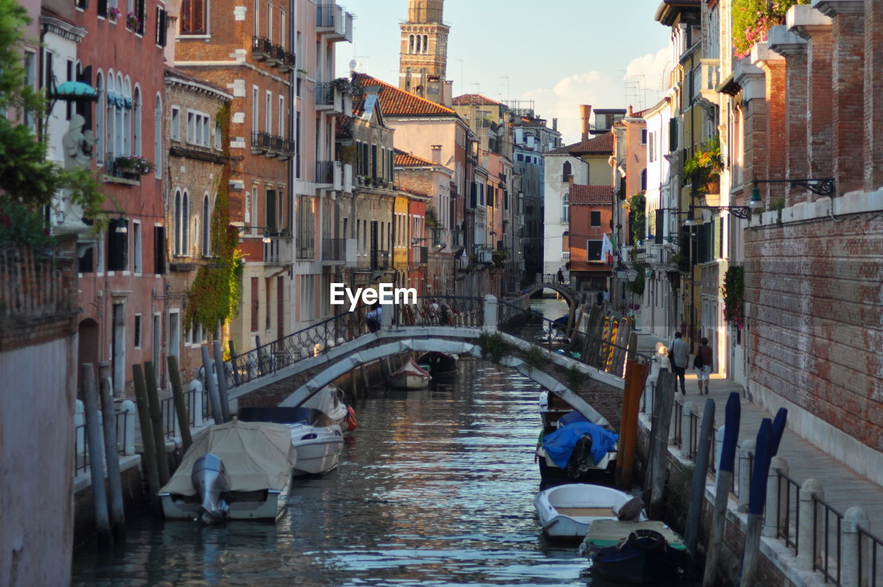 Boats moored on canal amidst buildings in city