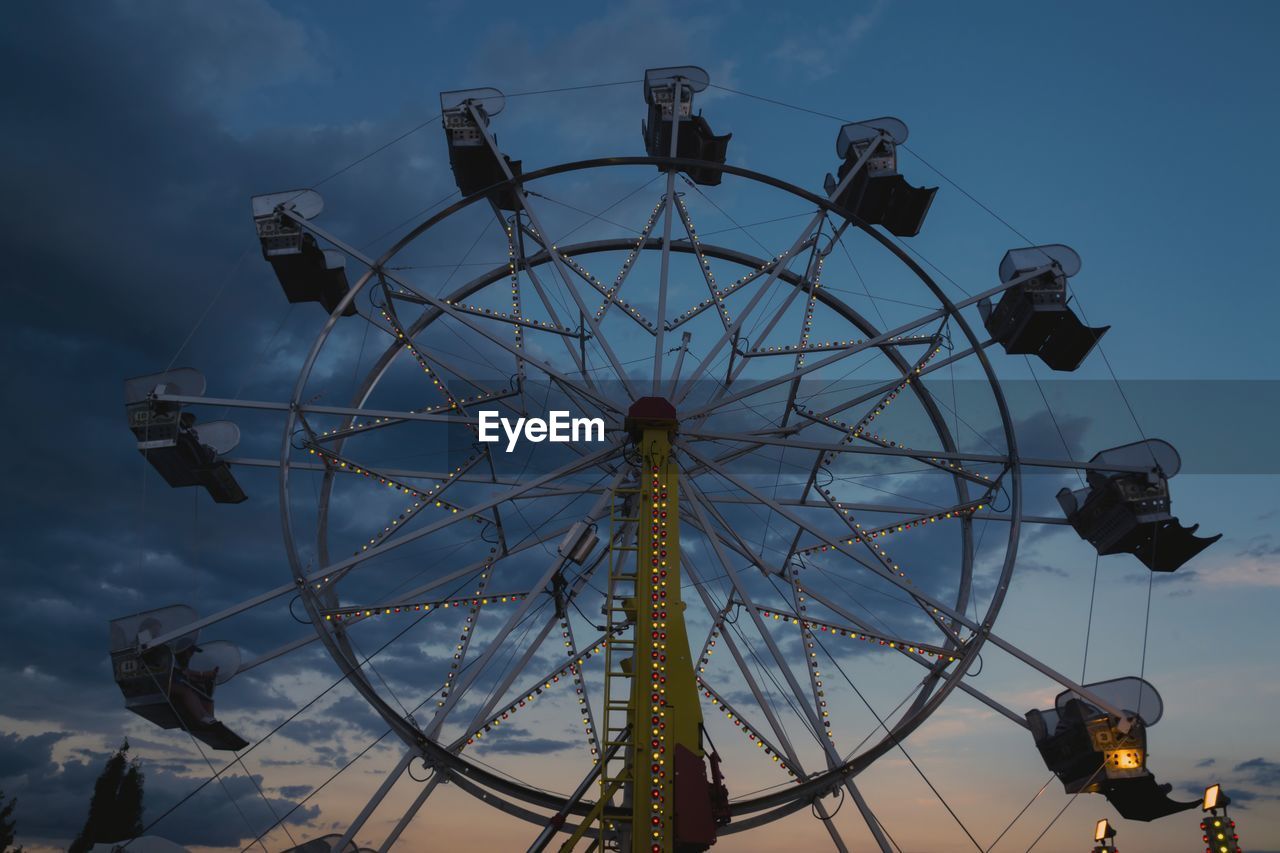 Low angle view of ferris wheel against cloudy sky during sunset