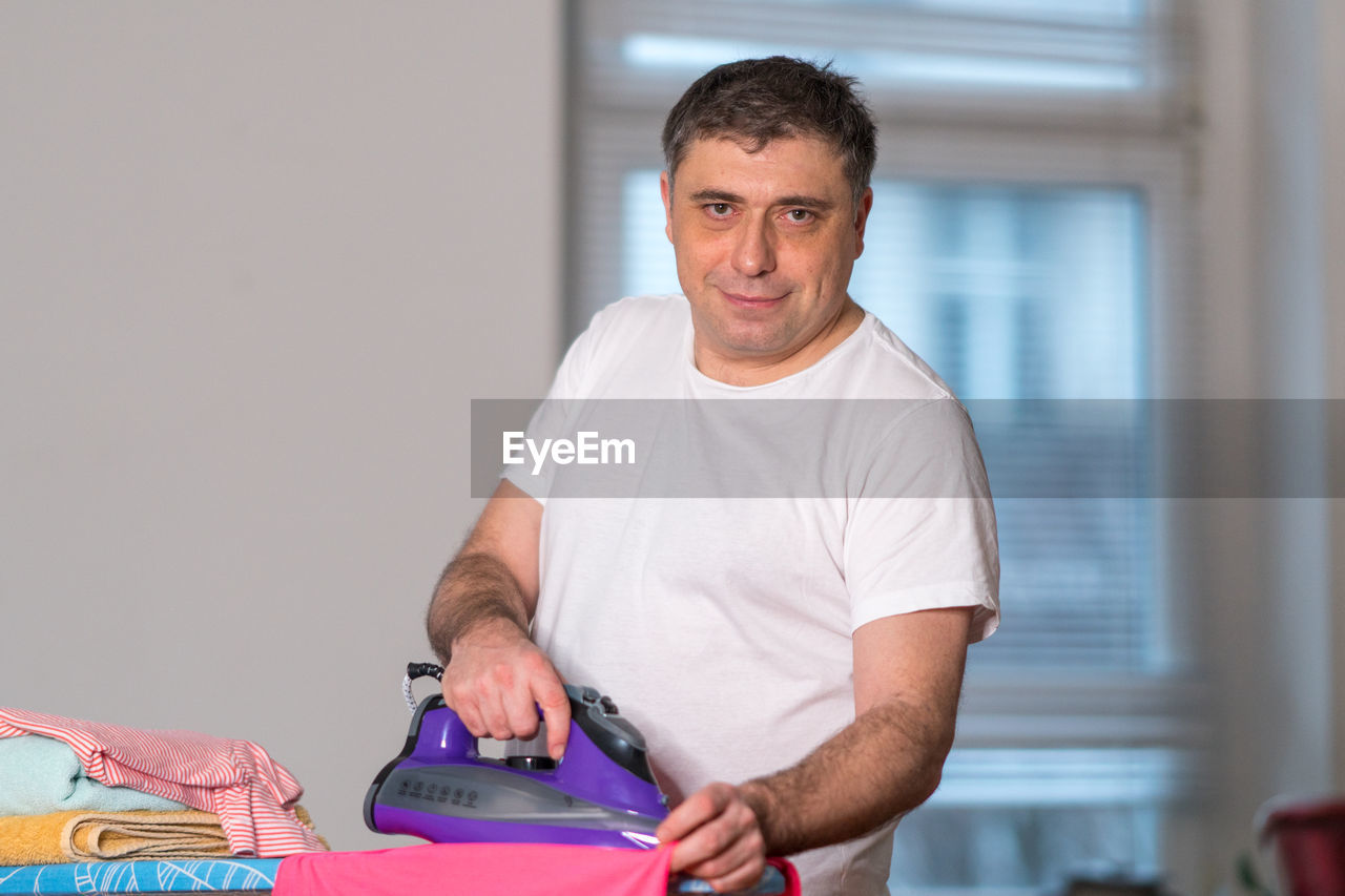 Portrait of man ironing cloth at home