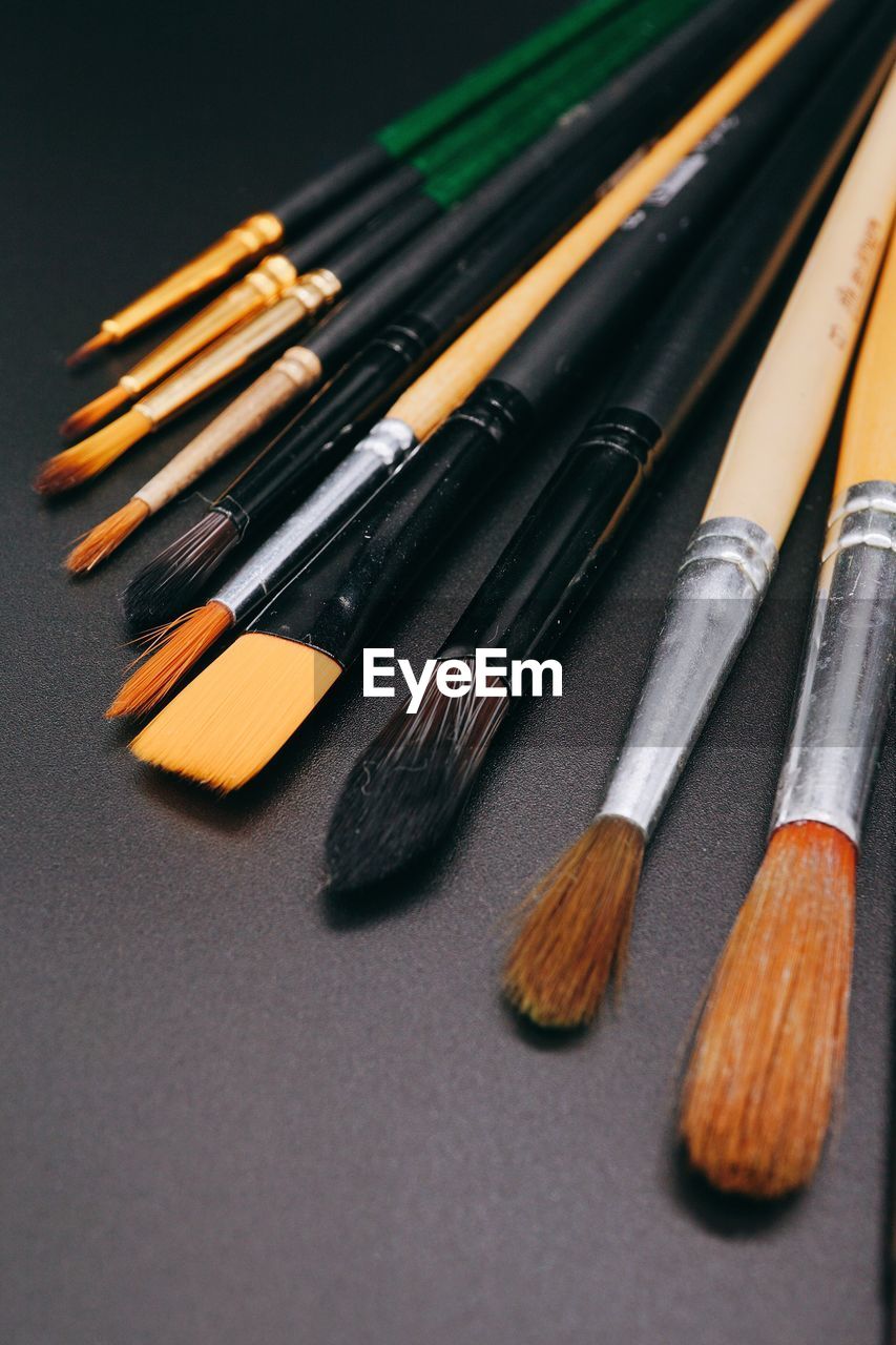 Close-up of various paintbrushes on black table