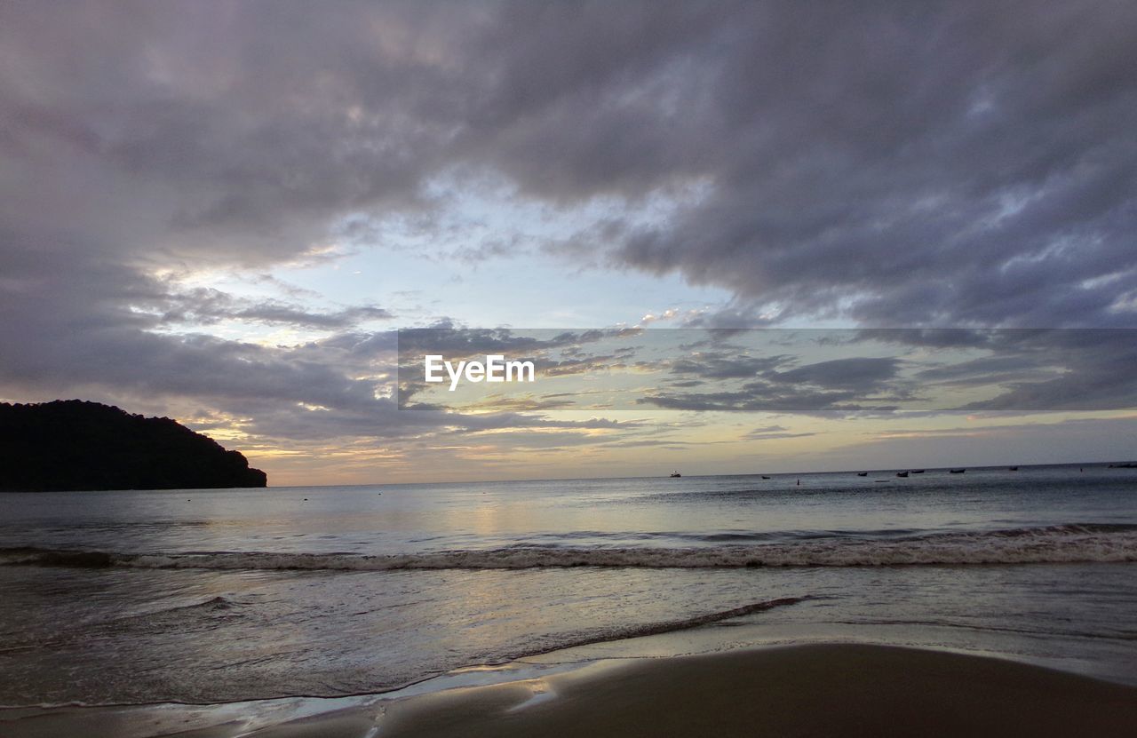 Scenic view of beach against cloudy sky