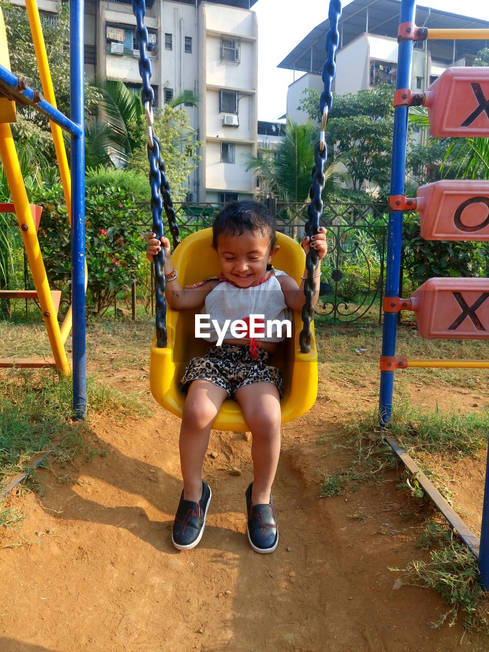 Smiling girl sitting on swing in playground