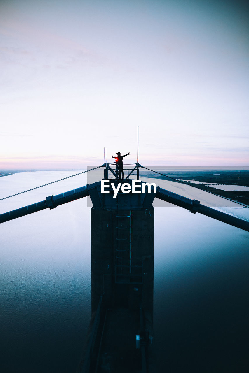 SILHOUETTE MAN STANDING BY RAILING AGAINST SKY