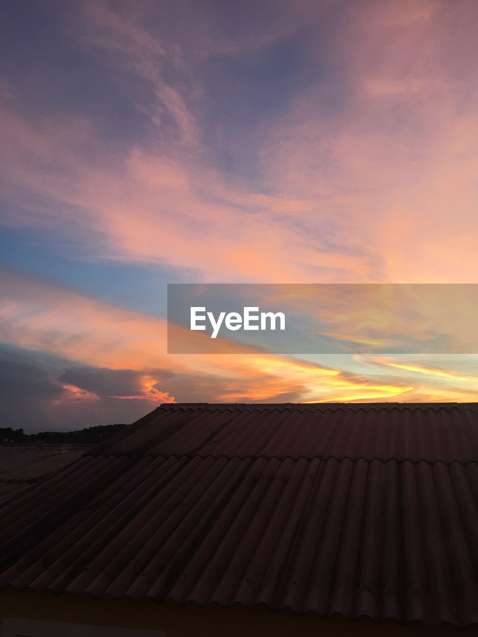 Roof of house against sky during sunset