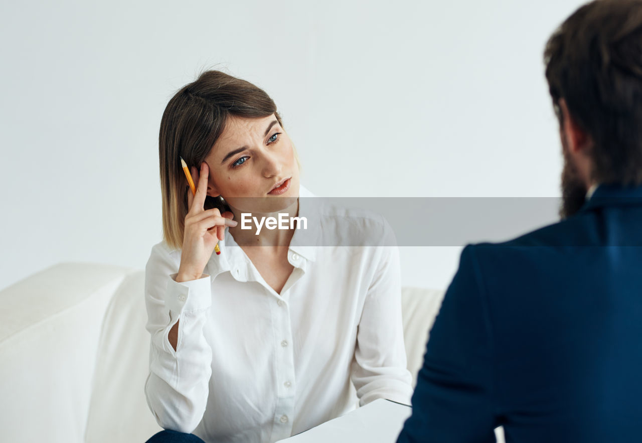 businesswoman using mobile phone while sitting on table in office