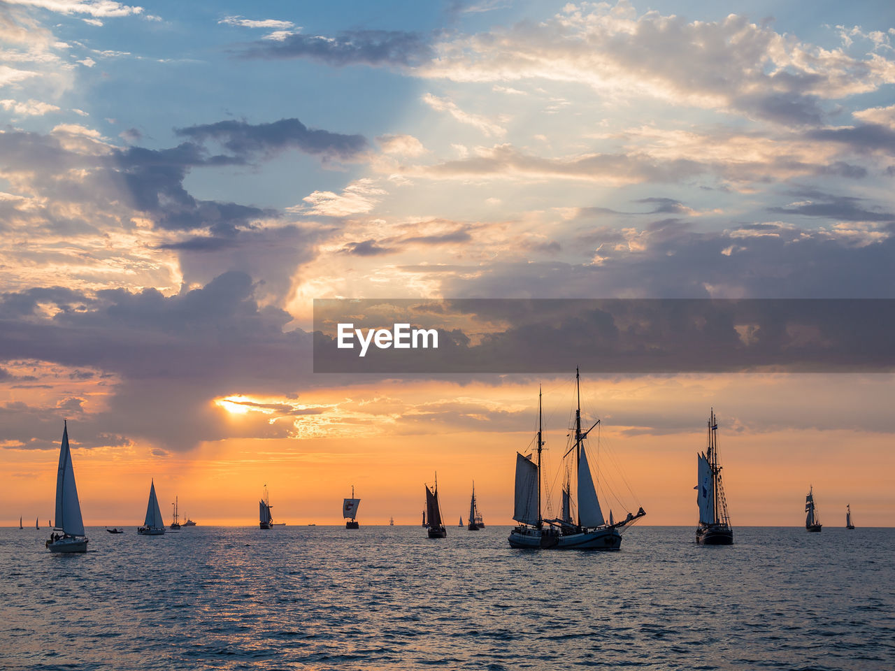 Sailboats sailing on sea against sky during sunset