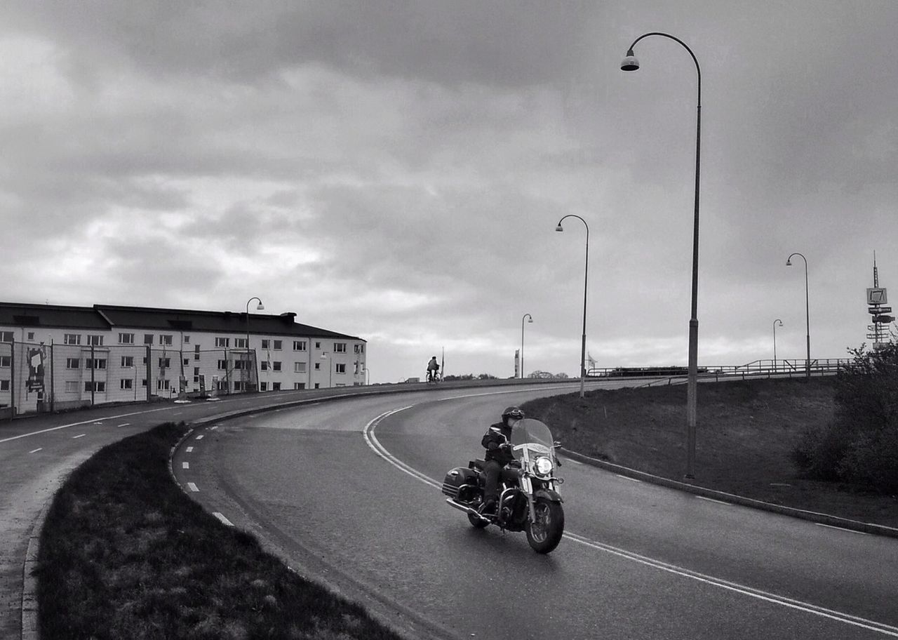 Motorbike on curved road against cloudy sky