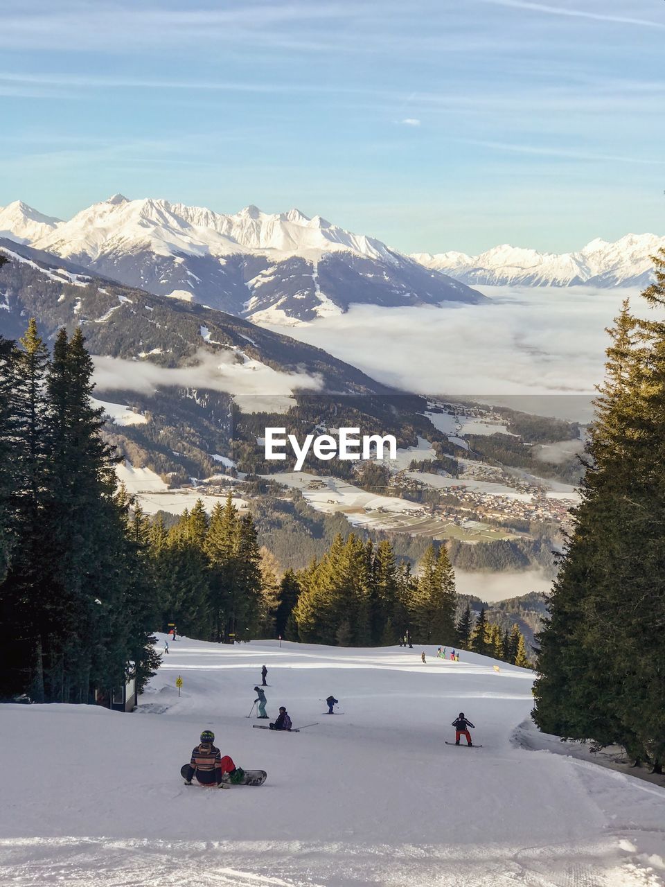 People on snowcapped mountain against sky