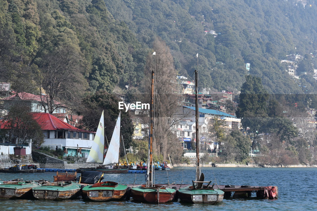 SAILBOATS MOORED ON SEA AGAINST MOUNTAIN