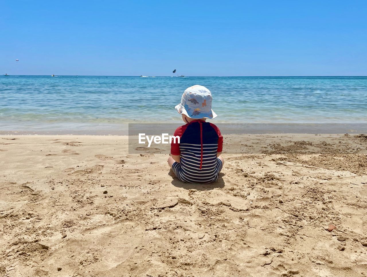 Rear view of boy sitting on beach