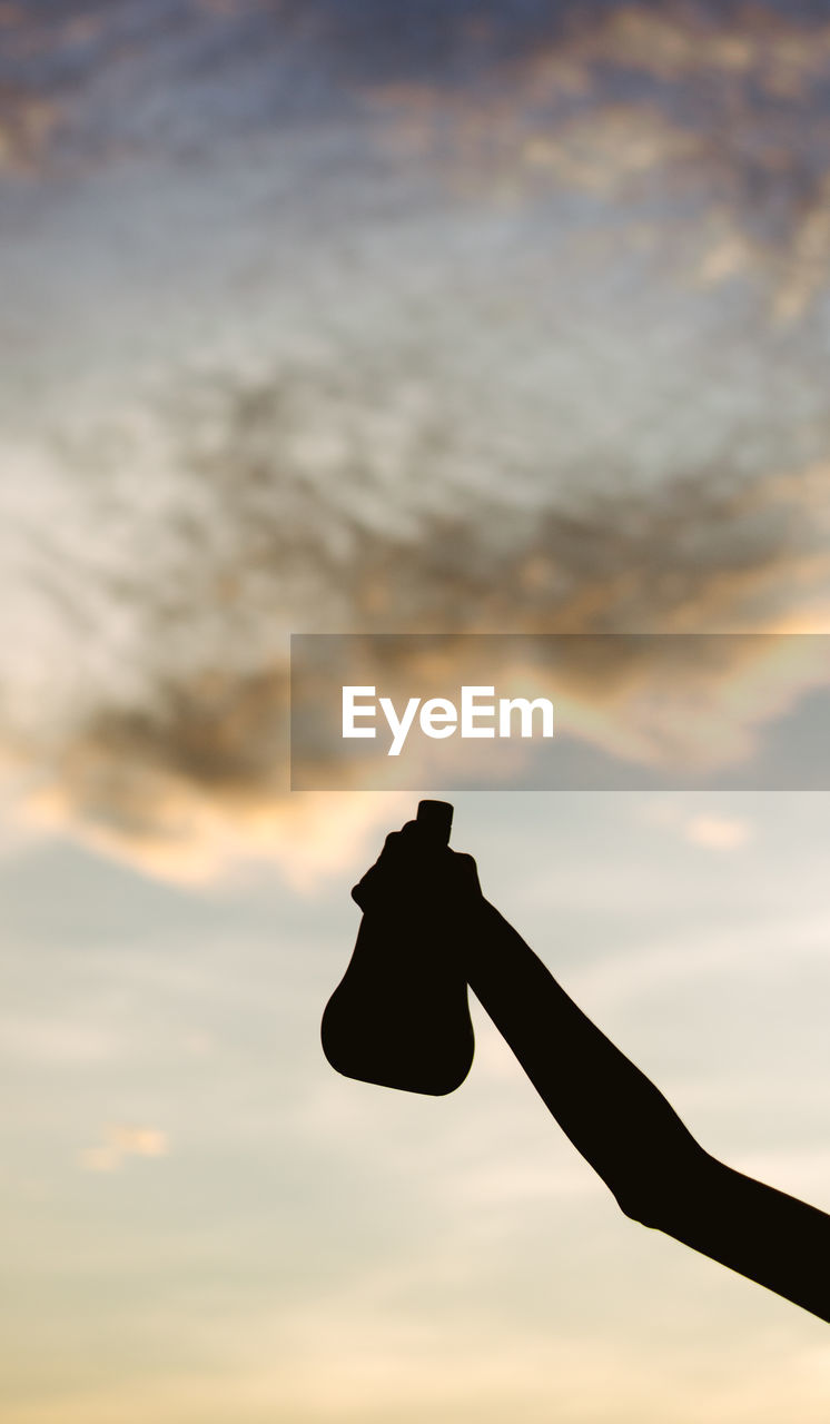 CLOSE-UP OF SILHOUETTE HAND HOLDING SUN AGAINST SKY