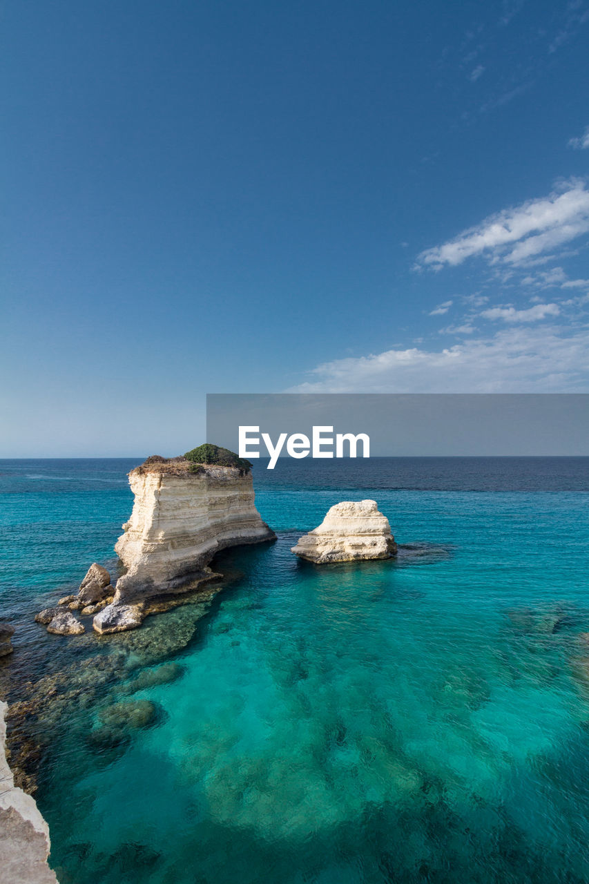 Scenic view of light blue and crystal clear sea against white clouds sky