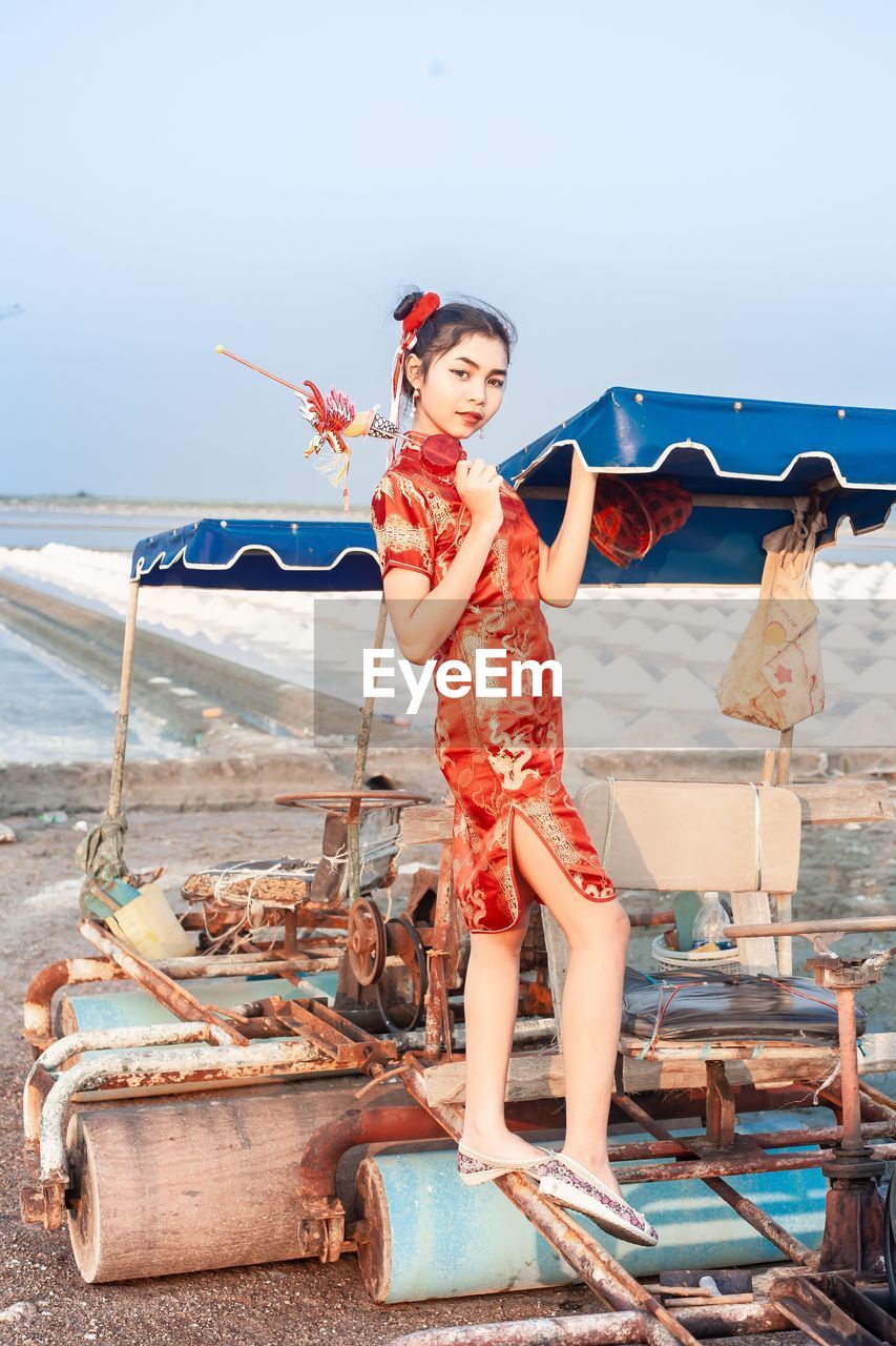 Full length of women in chinese culture costume standing on beach against sky