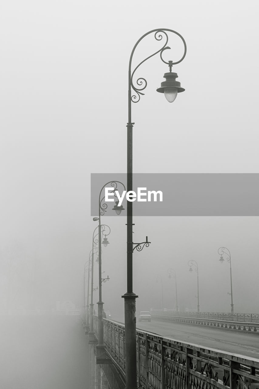 Street light by bridge against sky