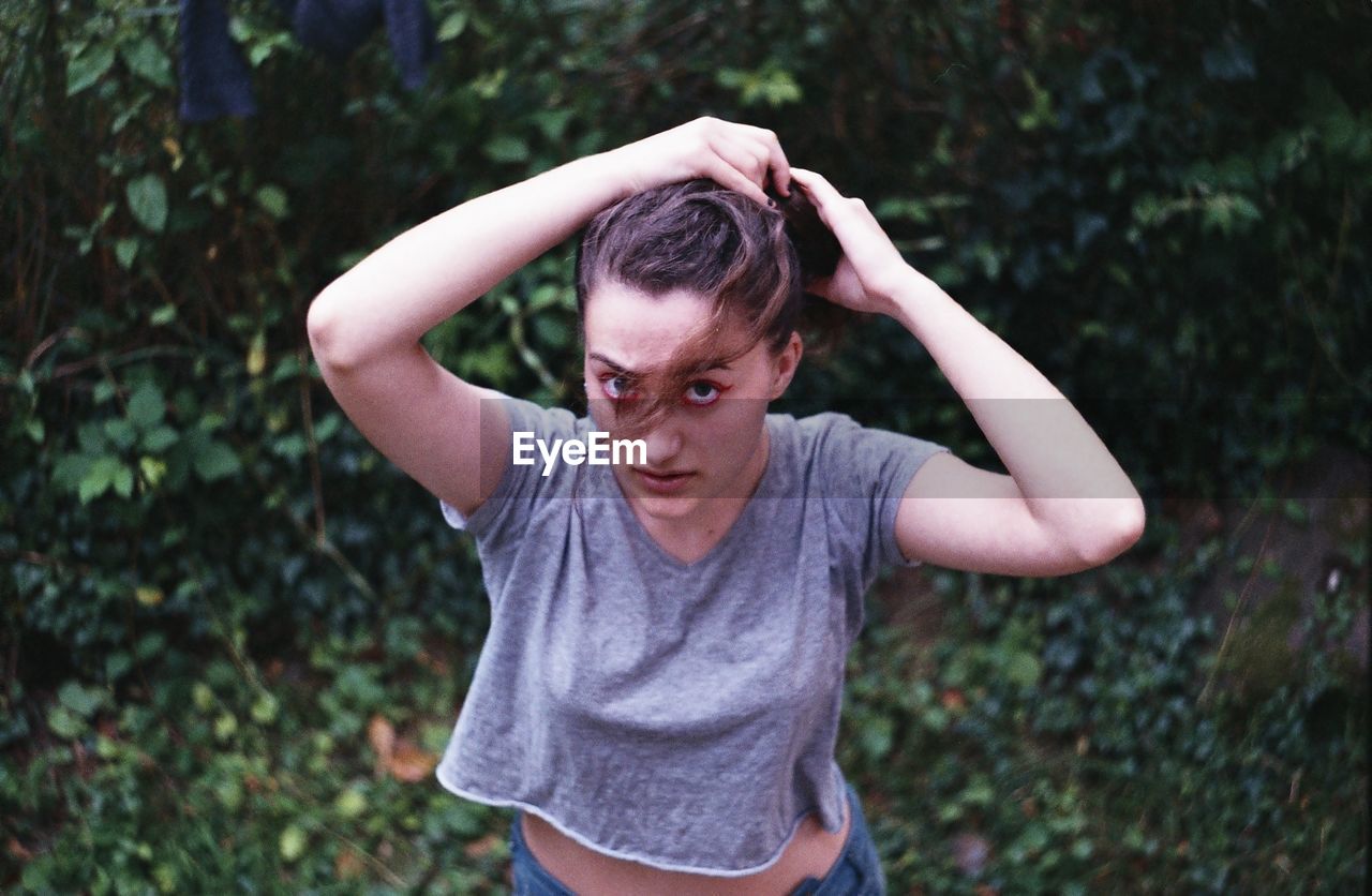 High angle portrait of young woman tying up hair