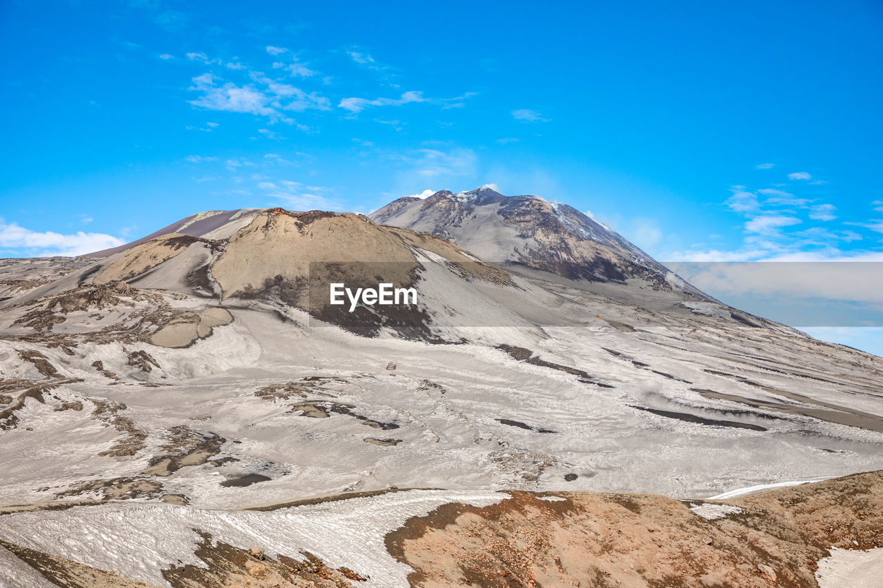 Scenic view of snowcapped mountains against blue sky