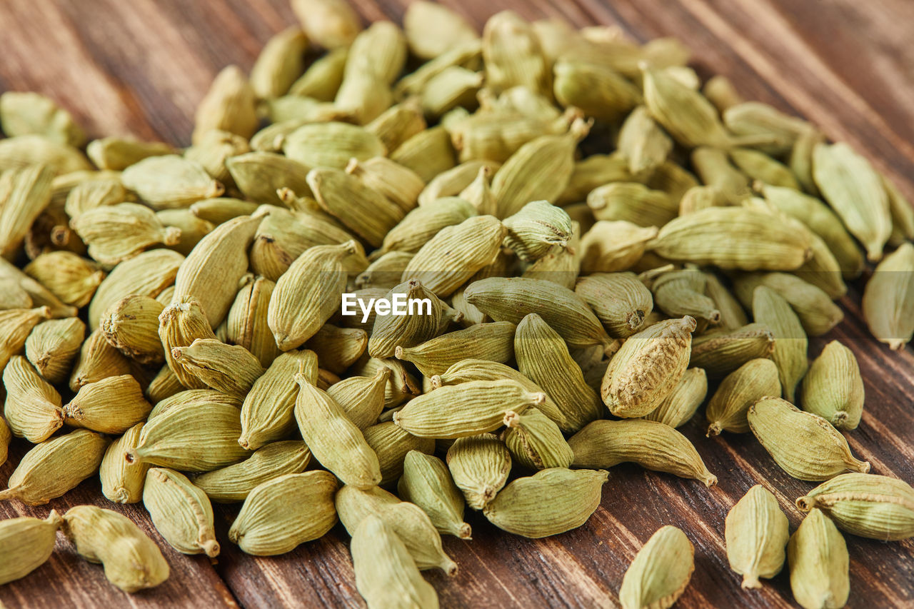 Green cardamom is scattered over vintage wood background