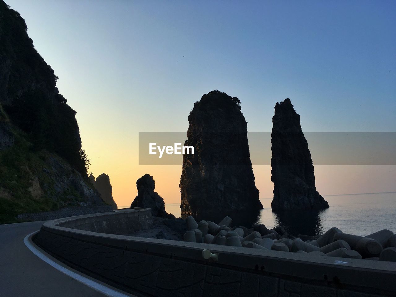 Rock formation by sea against clear sky