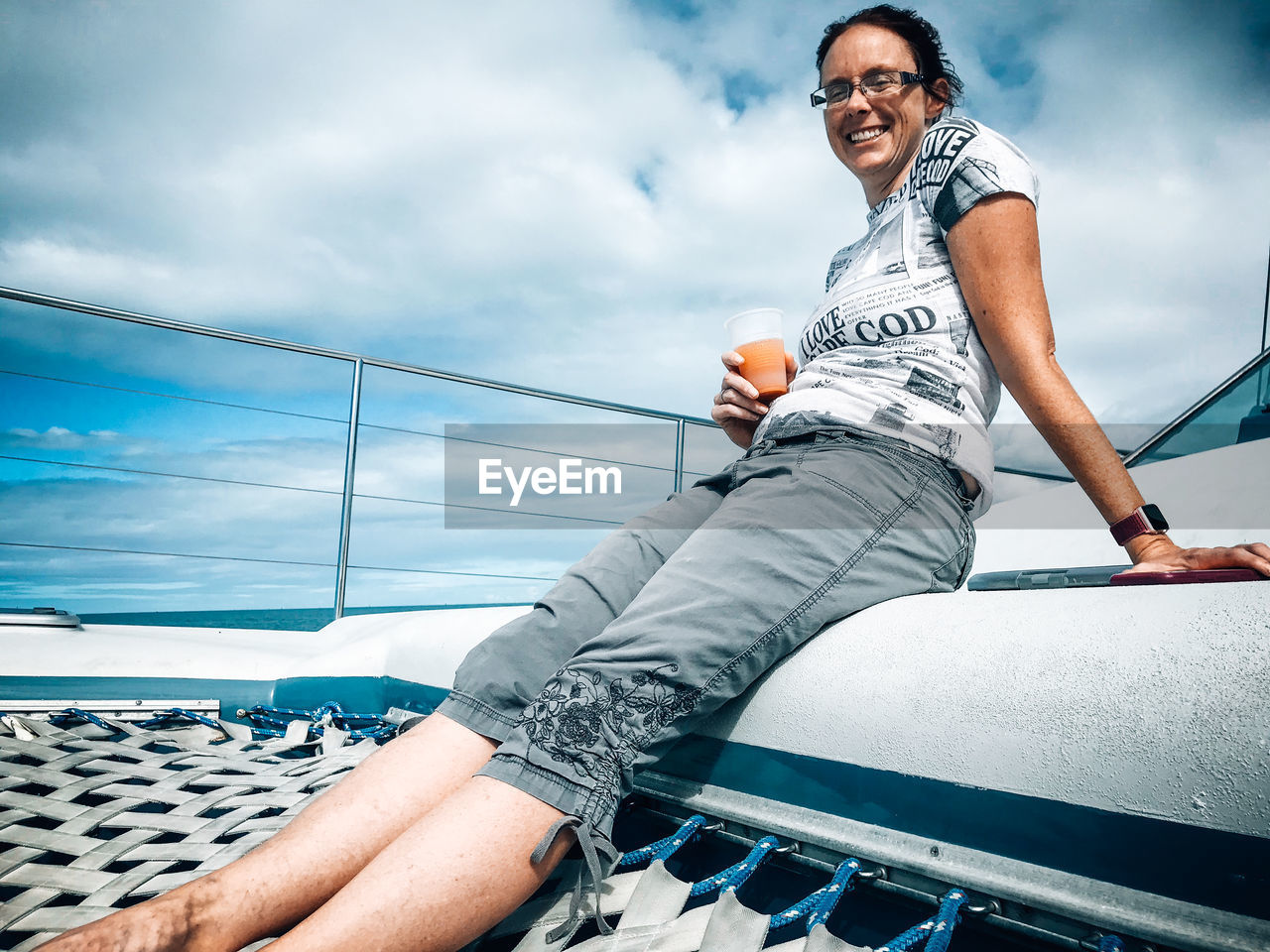 Low angle portrait of smiling woman sitting on boat against sky