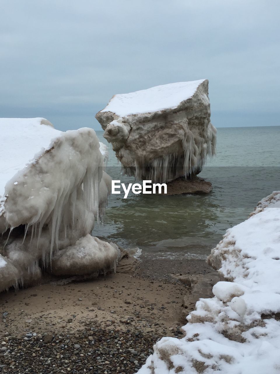 Frozen rocks at lake michigan against sky